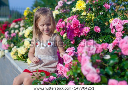 Portrait of cute little girl near the flowers in the yard of her house