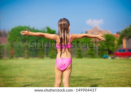 Back view of little girl in a swimsuit playing and splashing