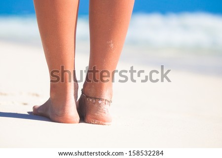 Women's beautiful smooth legs on white sand beach