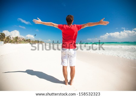 Back view of Young man enjoying the holiday spread his hands on tropical beach