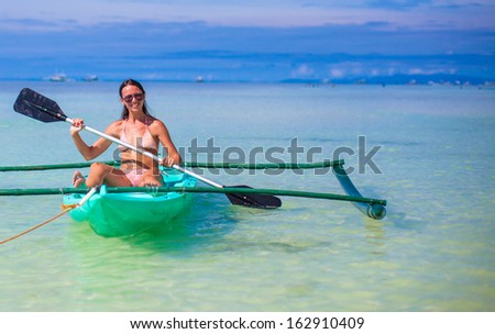 Young woman kayaking alone in the clear blue sea