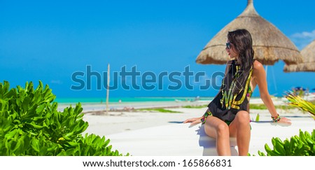 Young sexy woman sitting on a boat in white sandy beach