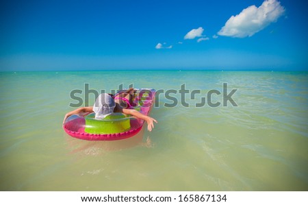 Little cute girl on pink air-bed in Caribbean sea