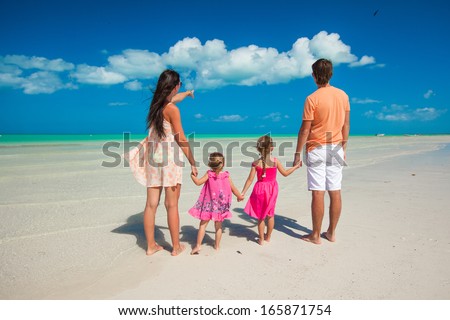 Back view family of four on caribbean beach vacation