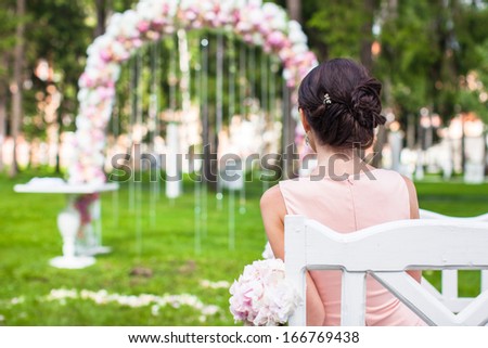 Back view of beautiful young woman in a long dress at the ceremony outdoors