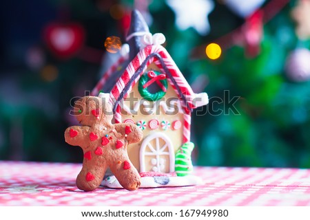 Gingerbread man in front of his candy ginger house background the Christmas tree lights