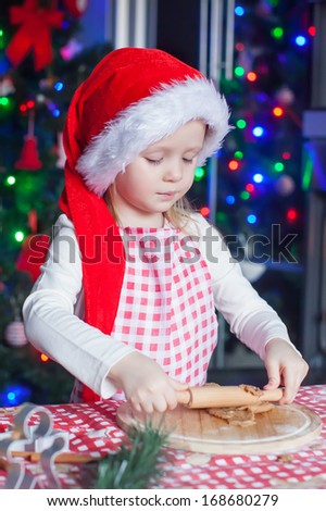 Adorable little girl in Santa hat  baking gingerbread Christmas cookies at home