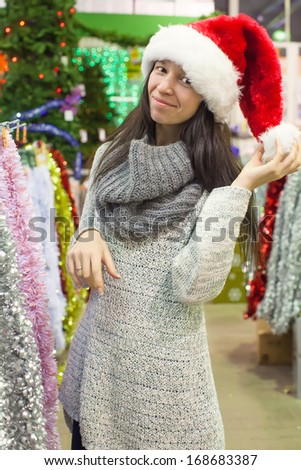 Young woman in santa hat choosing decorations on the Christmas tree