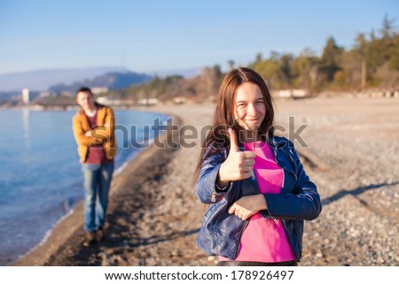Young couple together on an empty beach in winter sunny day