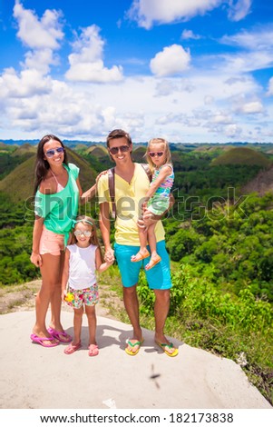 Young family of four on a background the Chocolate Hills in Bohol