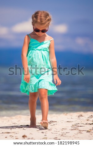 Adorable little girl walking on tropical white beach at desert island