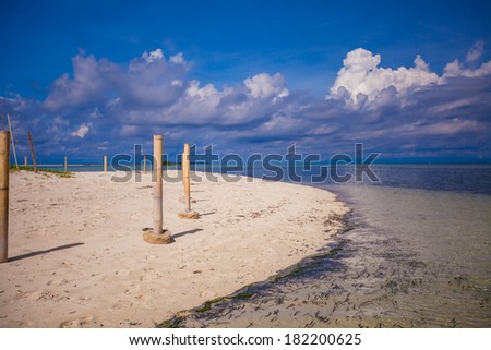 Perfect white beach with turquoise water and a small fence on desert island