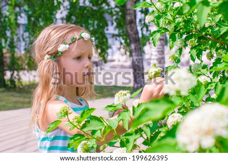 Little adorable girl near white flowers in the garden