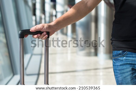 Close-up of a man with luggage in airport while waiting the flight