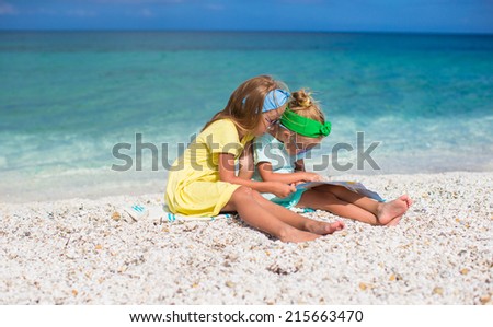 Little cute girls with big map on tropical beach vacation