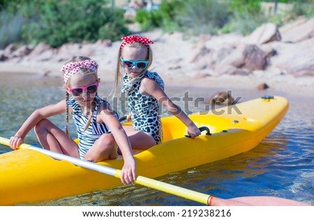 Little adorable girls enjoying kayaking on yellow kayak in the clear turquoise water