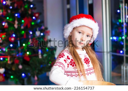 Adorable little girl baking gingerbread cookies for Christmas