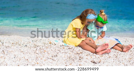 Little adorable girls with big map on tropical beach vacation