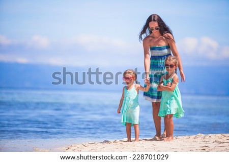Adorable little girls and young mother on tropical white beach in desert island