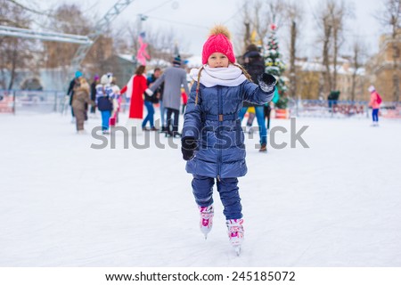 Cute little girl skating on the ice rink outdoors