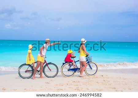Young happy family riding bicycles duting beach vacation