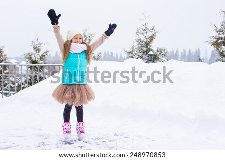 Adorable little girl skating in winter snow day outdoors