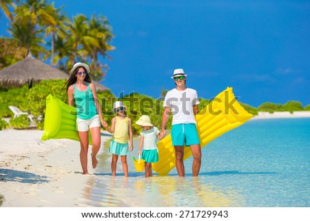 Happy beautiful family on white beach with inflatable air mattresses and toys