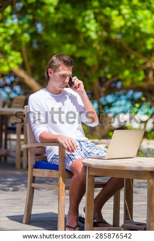 Young business man calling by cell phone in outdoor cafe