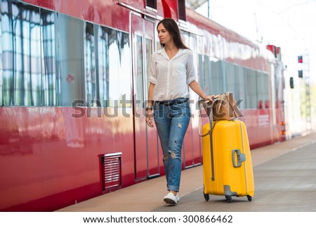 Young happy woman with luggage at a train station