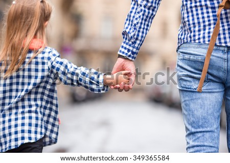 Hands of man and child holding together on street at european city
