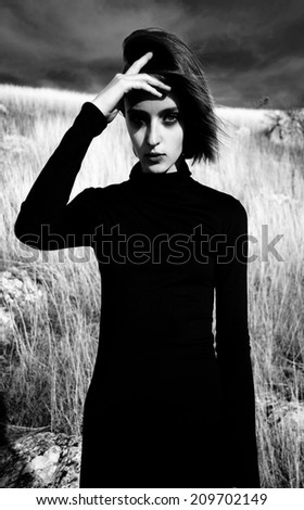 girl with a strong face in a black dress in a landscape