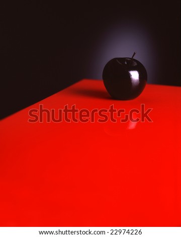 Black apple on the red table