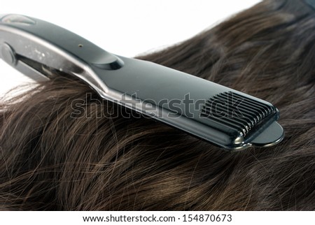 Hair straighteners and hair on white background