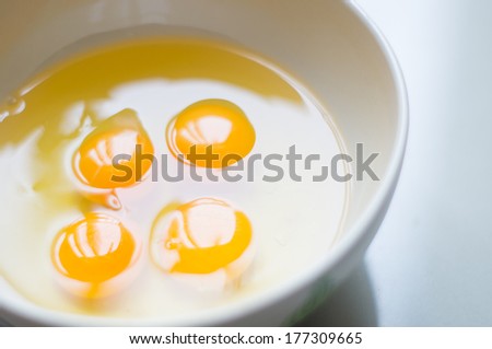 Four yellow egg yolks in a white bowl.
