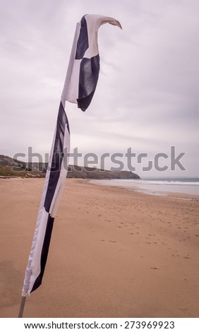 Praa sand in cornwall england uk. Stunning coastline and sandy beaches. Life saving black and white flag for surfers
