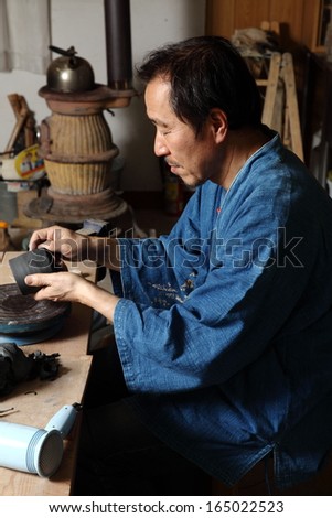 Japanese pottery master/The inspection/Japanese pottery master in his studio inspecting the detail of his work.