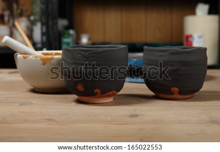 Japanese pottery cups/Halfway there/Two Japanese pottery cups drying after being coated by a special mixture from inside a Japanese pottery master\'s studio