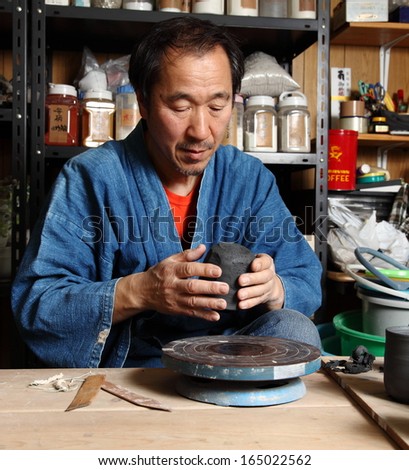 Japanese pottery master/The inspection 2/Japanese pottery master in his studio inspecting the detail of his work from another angle.