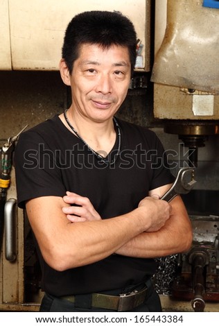 Japanese small business owner portrait/Satisfaction guaranteed/A head and shoulders portrait of a Japanese small business owner inside his small metal workshop.