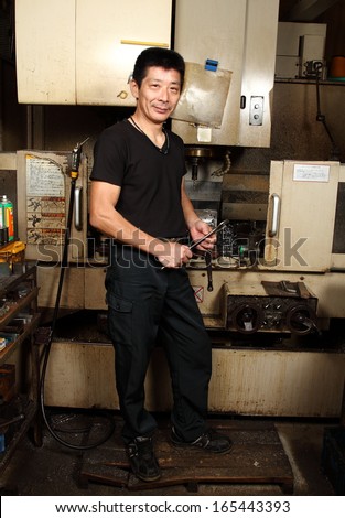 Japanese small business owner full length portrait/Satisfaction guaranteed 2/ A full length portrait of a Japanese small business owner inside his small metal workshop.