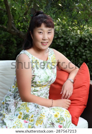 Beautiful Japanese lady outdoor/Happy Japanese lady/A photo of a beautiful middle aged Japanese lady sitting on outdoor furniture in a garden at Lake Como, Italy. 3/4 portrait.
