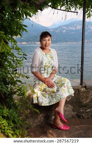 Beautiful Japanese lady outdoor/Happy Japanese lady/ A photo of a beautiful middle aged Japanese lady under the shade by Lake Como in Italy. Full length portrait.