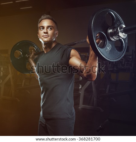 Confident muscular man training squats with barbells over head. Closeup portrait of professional bodybuilder workout with barbell at gym.