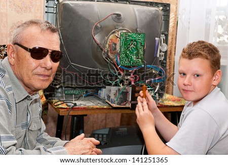 Grandfather and grandson are repairing an old TV