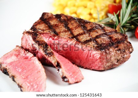 sliced grilled steak on white plate with veggies