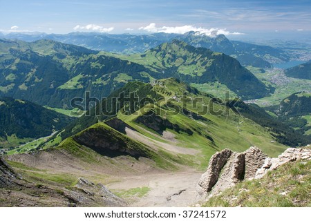 Summer Alpine landscape. Green mountain ridge. Horizon line with some clouds