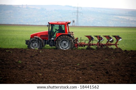 Red tractor working at field
