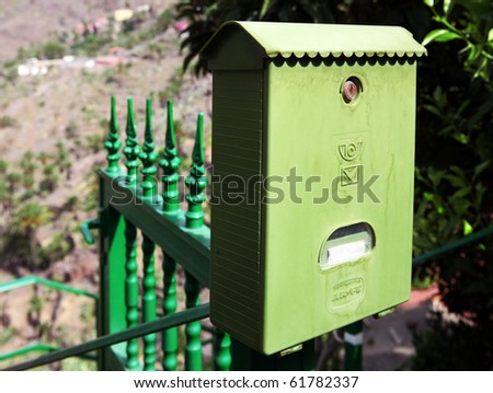 Old mailbox on the green fence with tree behind