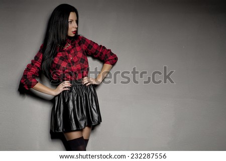 Elegant young brunette woman posing in beautiful black skirt and red shirt. Girl with long hair.
