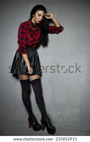 Young beautiful woman wearing black leather skirt, stockings and grille shirt